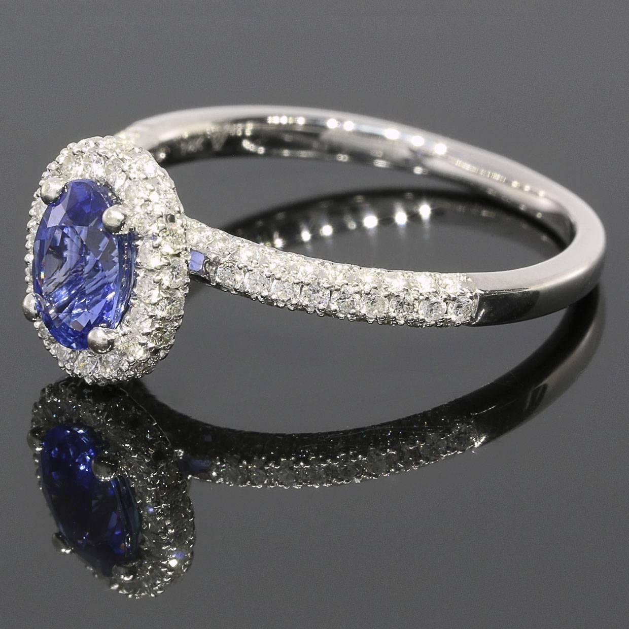 This lovely engagement ring has a beautiful diamond encrusted, halo design that gives a really classic & sparkly look! The ring features an oval brilliant cut, lab created, blue sapphire center that weighs 1.20 carat & is GGL certified. This