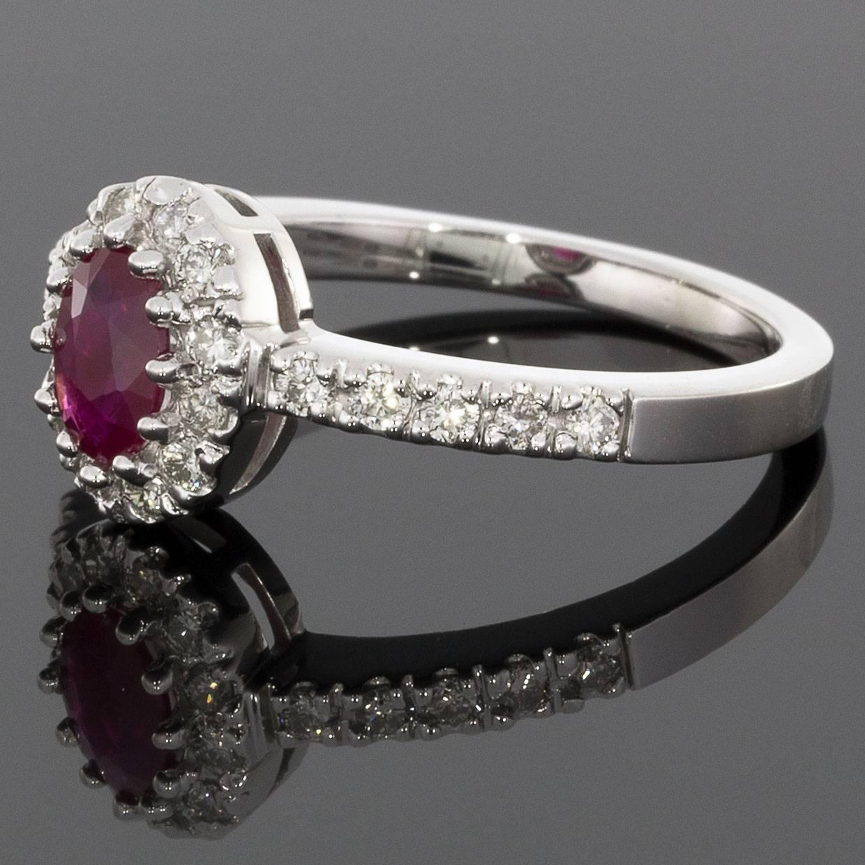 This lovely ruby ring has a timeless diamond halo design that gives a really sparkly look! The ring features an oval brilliant cut, natural, ruby center that is multi, shared prong set in white gold. This beautiful ruby is surrounded by a dazzling