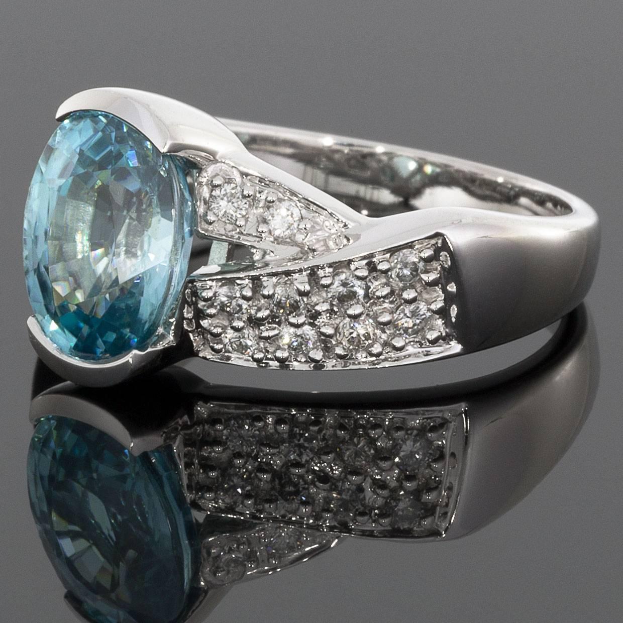 This stunning blue zircon & diamond ring is perfect for dressing up any outfit! Its tranquil blue zircon, sparkling diamonds, & icy white gold will go with everything. It features a 4.0 carat, oval brilliant cut, blue zircon that is securely