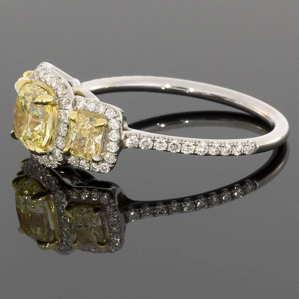 This alluring ring features a classic yet stunning halo design. This design showcases the stunning fancy yellow, cushion brilliant cut center diamonds with yellow gold prong settings surrounded by white diamonds & white gold in a custom made