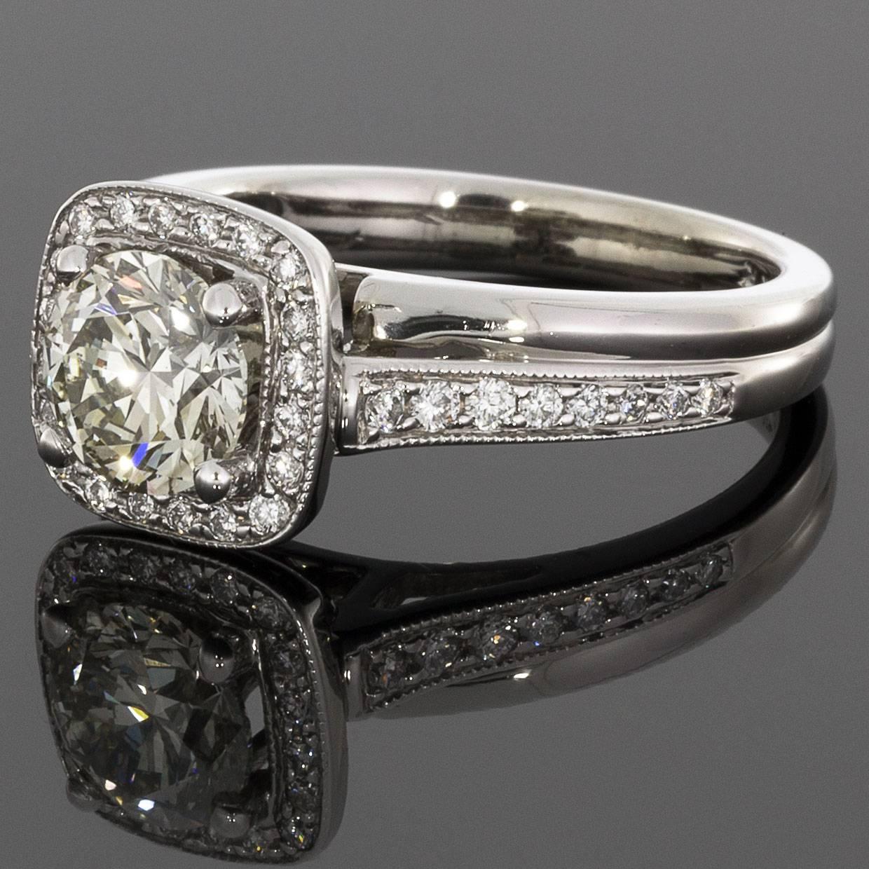 This beautiful engagement ring has a unique & beautiful bypass halo design. The ring features a round brilliant cut diamond center that weighs approximately 1.25 carat & grades as M/SI1 in quality. This glistening diamond is surrounded by a