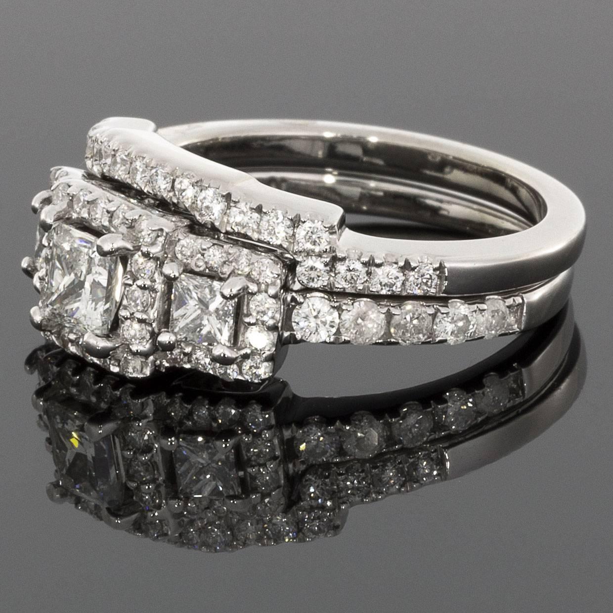This lovely wedding set features an absolutely beautiful halo three stone design. The three main diamonds are princess cut diamonds that grade as I/I1 in quality & are framed by sparkling round brilliant cut diamond halos. Additional round