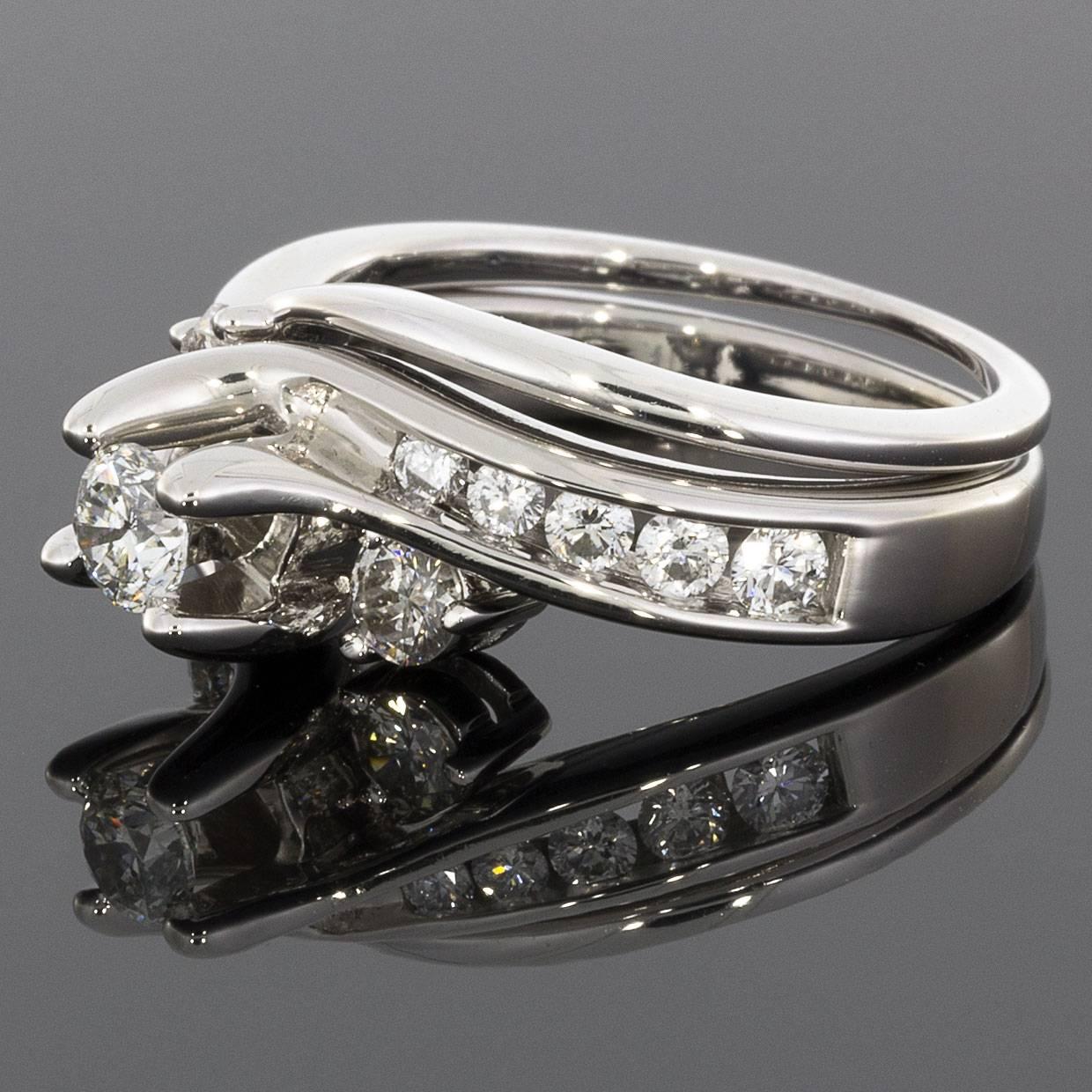 This beautiful engagement ring & wedding band set features a lovely bypass or swirl design in 14 karat white gold. The channel set diamond shoulders of the ring flow gracefully to form the center diamond's prongs. The center diamond is a .25