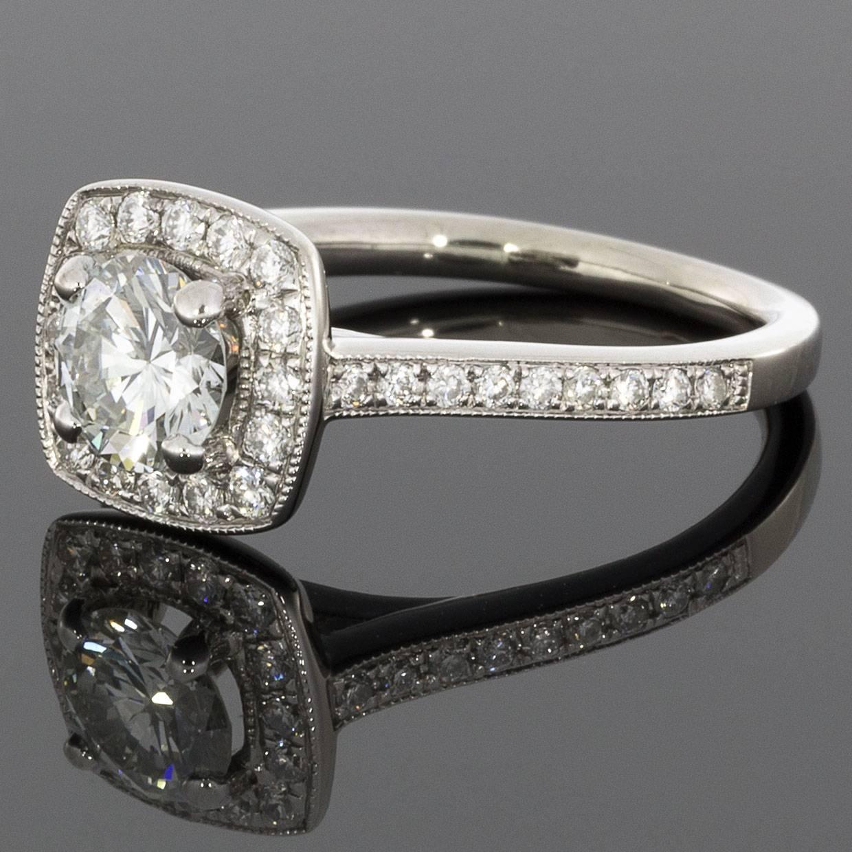 This lovely engagement ring has a classic cushion halo design. The ring features a round brilliant cut diamond center that weighs .70 carat & grades as H/VS2 in quality. This glistening diamond is surrounded by a cushion shaped halo of prong set