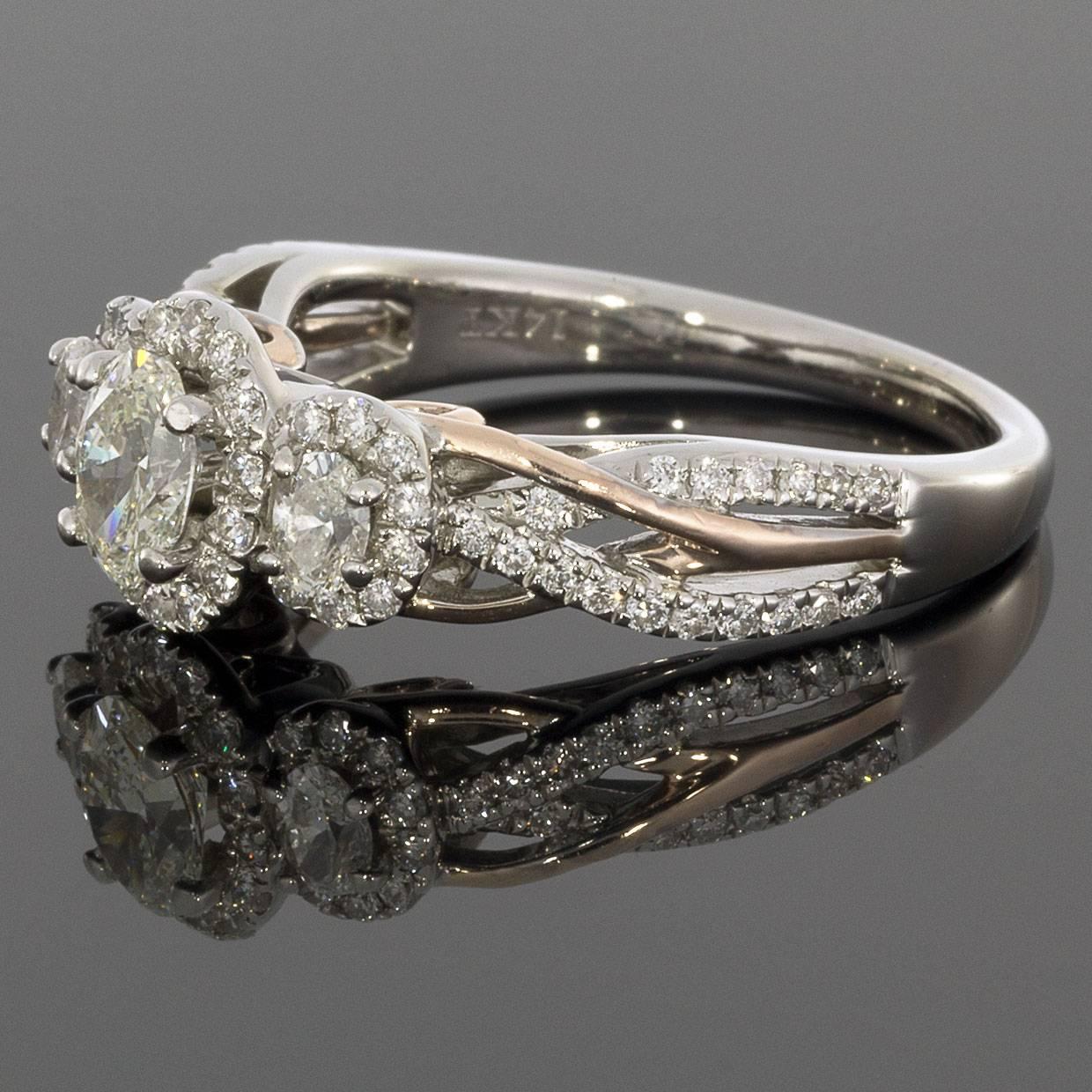 This beautiful halo engagement ring is absolutely radiant in the shine of white gold! Sure to render her speechless, the ring features 3 stones and a total carat weight of 1.0 carat. The Oval cut center diamonds are HI/SI1 in quality. These lovely