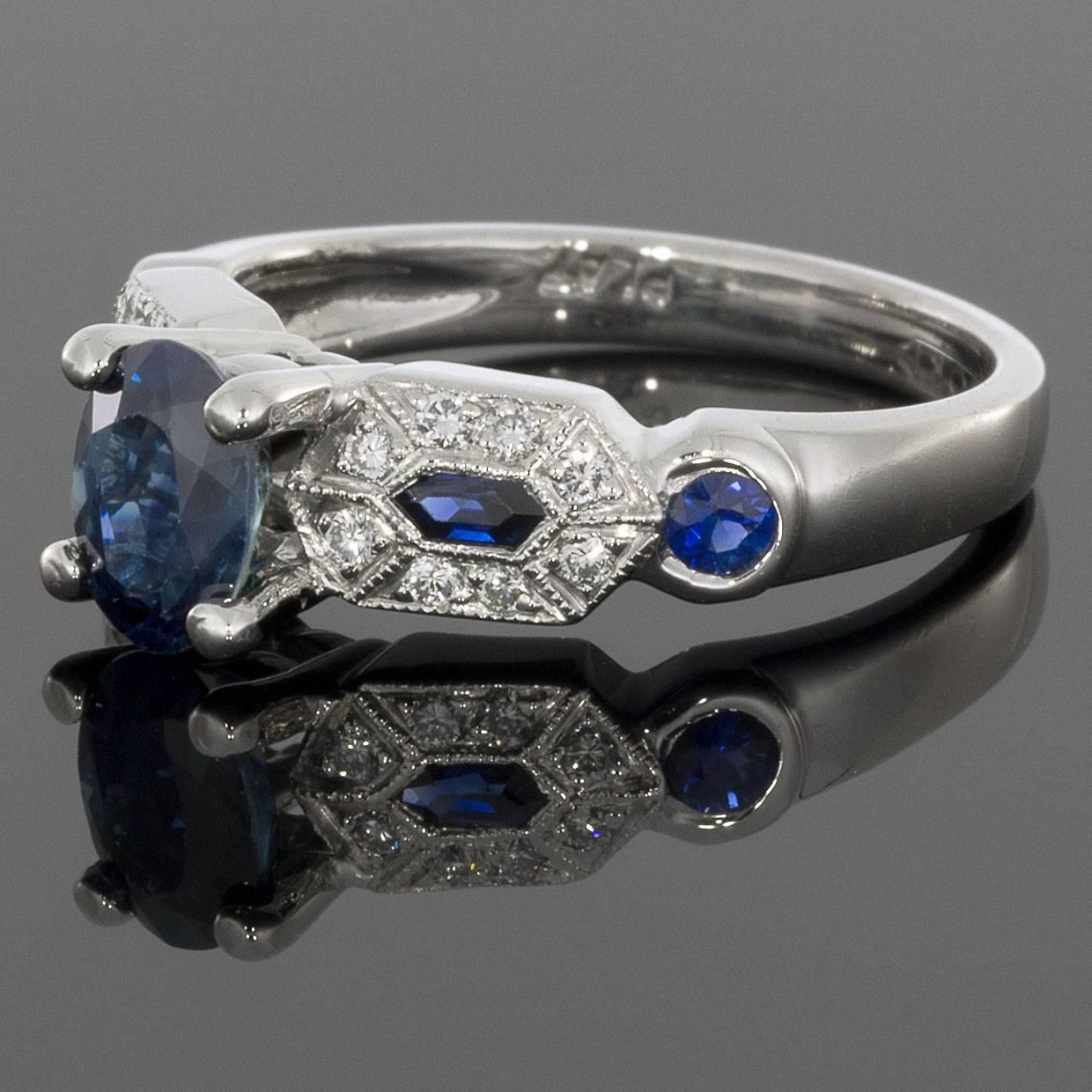 This amazing ring features a unique & beautiful combination of natural blue sapphires & sparkly white diamonds. The center of the ring is set with an oval sapphire weighing 1.11CTW. Pave diamonds and sapphires set in an Art Deco design flank either