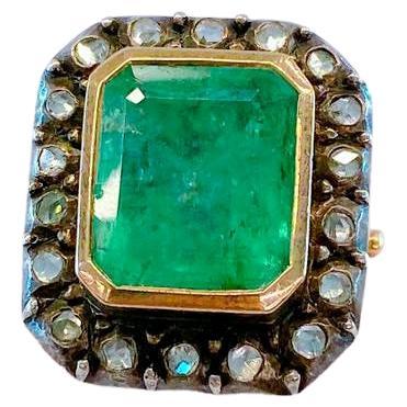 Antique ring centered with large natural green emerald diameter of 11mm×13mm in emerald cut inclusions included estimate emerald weight is 6 to 7 carats flanked with little rose cut diamonds estimate weight 0.50 carats in gold ring setting topped