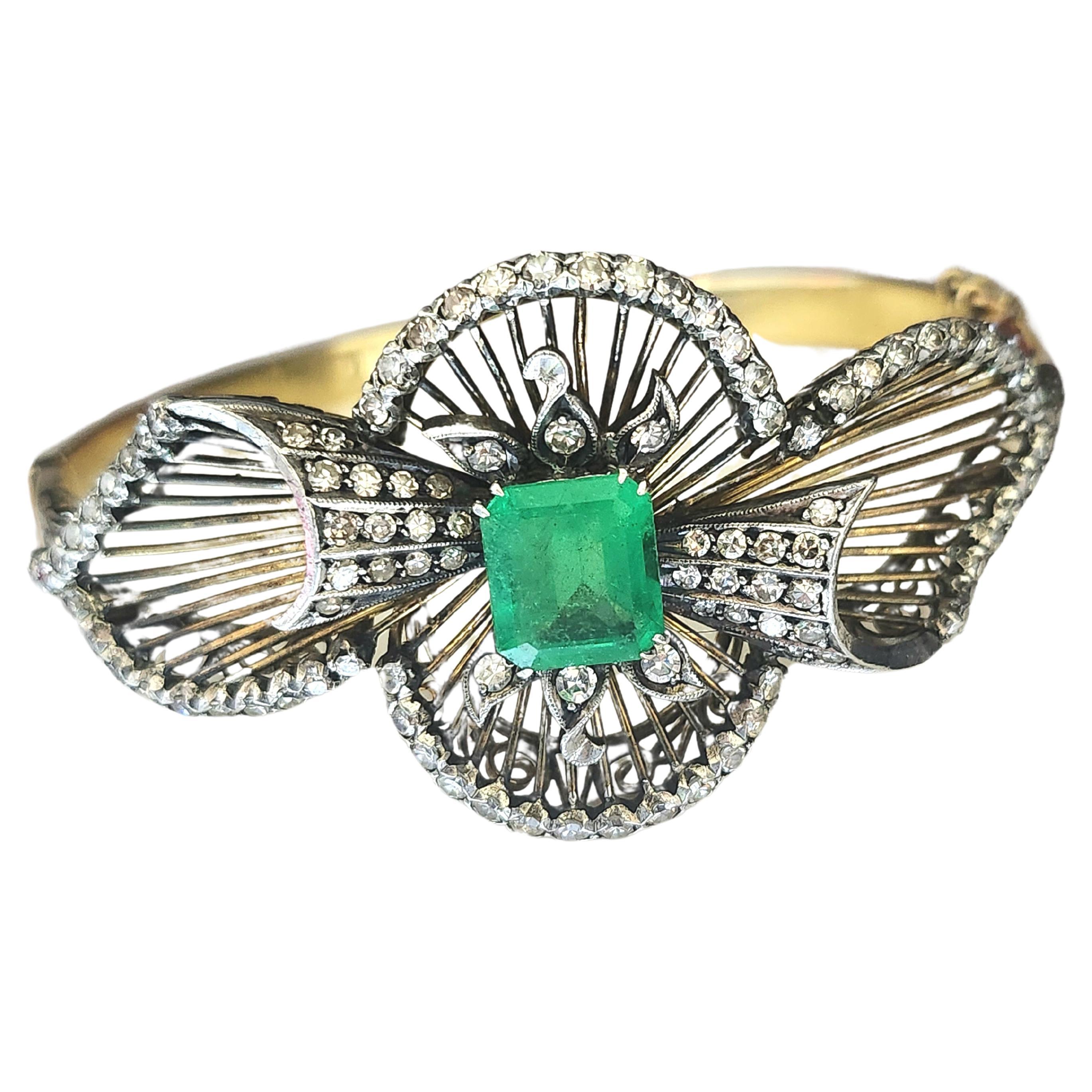 Antique bangle bracelet made in europe 1850s in an unuswal ribbon designe with detailed workmanship centered with natural green emerald 9.20mm×8mm estimate weight 3 carats flanked with old cut diamonds in open work style braclete head diameter