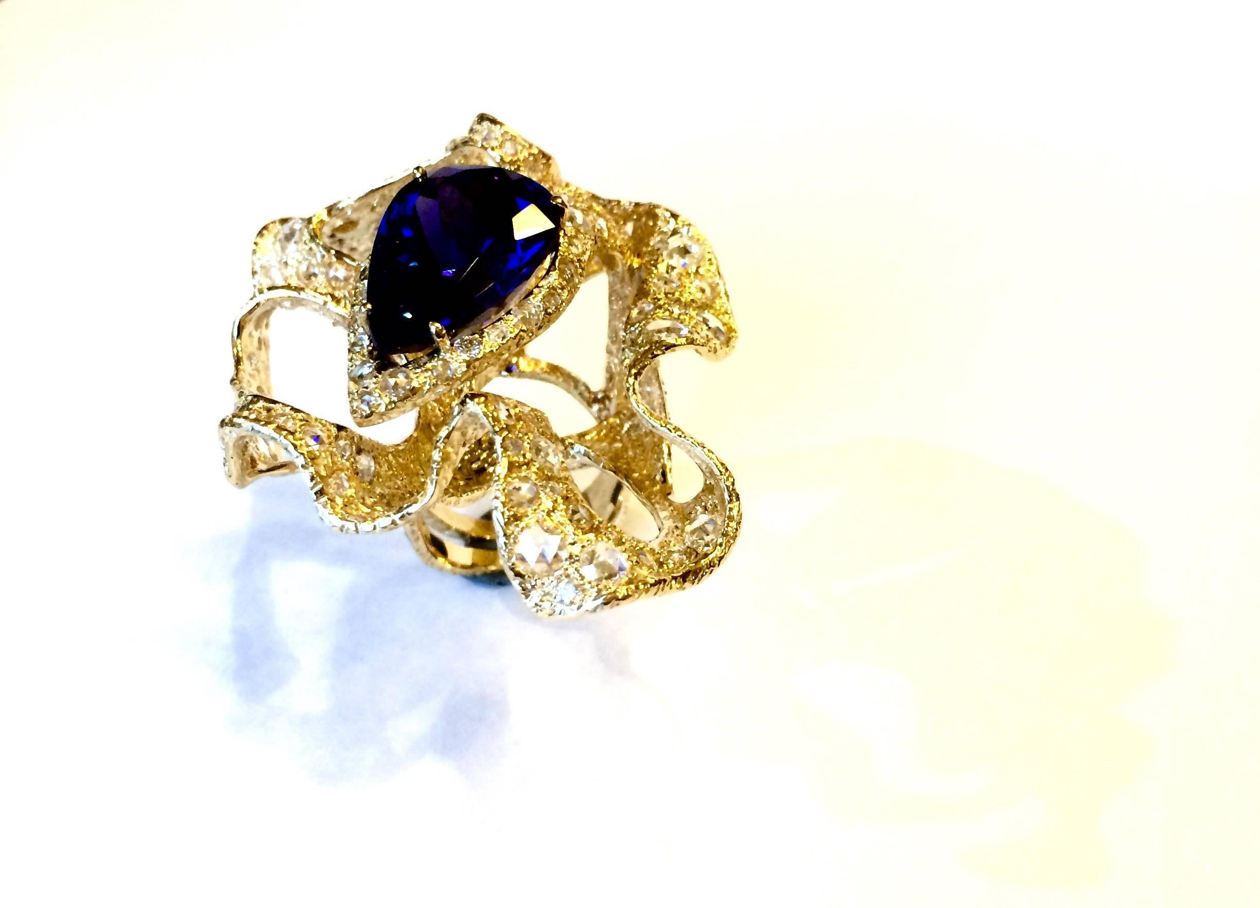 
18 Carats Gold Cocktail Ring Features a Stunning Natural Vivid Blue 15,41 Carat Pear Shape Tanzanite set with Rosette Cut and Round Diamonds.

This unusual ring is part of Andrea Ghelli's last collection, inspired by nature and flowers. 
It has