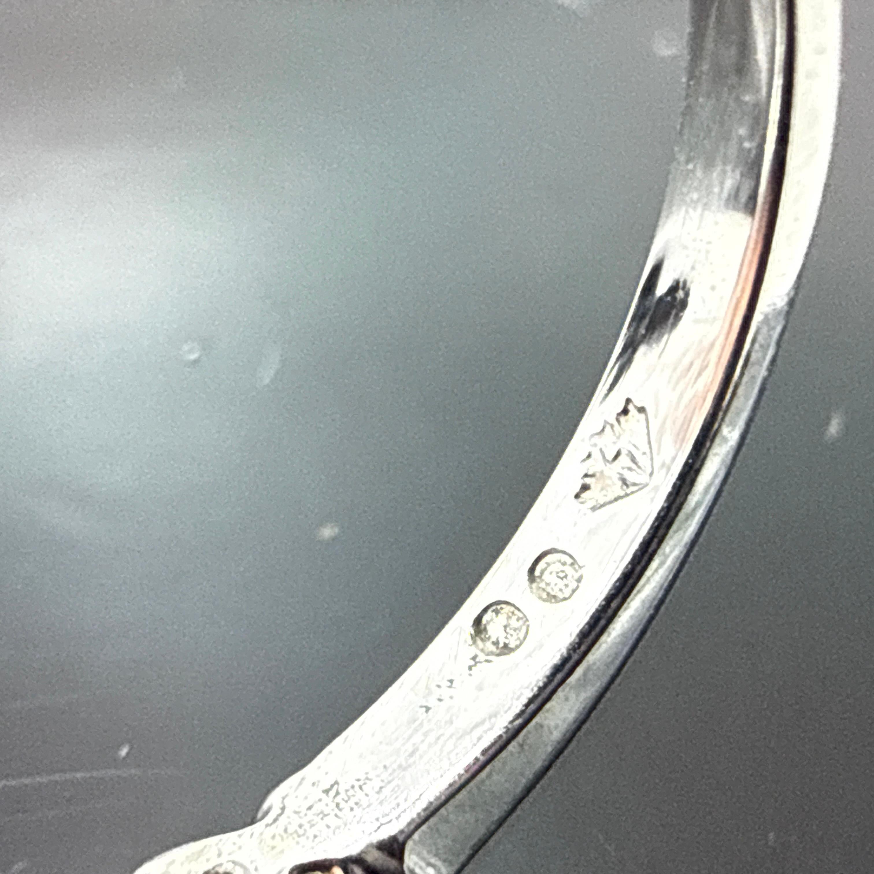 Cette bague en or blanc 14 carats présente un design classique à plusieurs pierres avec un diamant rond central de taille brillant flanqué de pierres latérales graduées. La bague est coulée à la cire, assemblée à la main et finie avec une surface