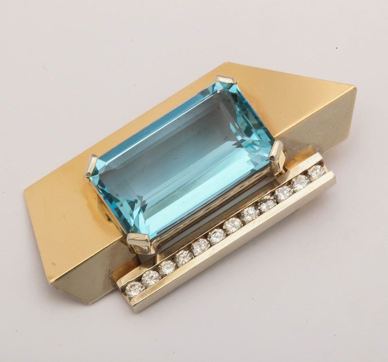 Modernist Aquamarine Pendant Brooch Prong set in 14 kt Yellow Gold mounting  with a row of Channel set Diamonds.  Has additional slide on fitting to be worn as a pendant.  Ca 1980.  Beautiful deep Aqua weighing approximately 30 cts. Clean & crisp in