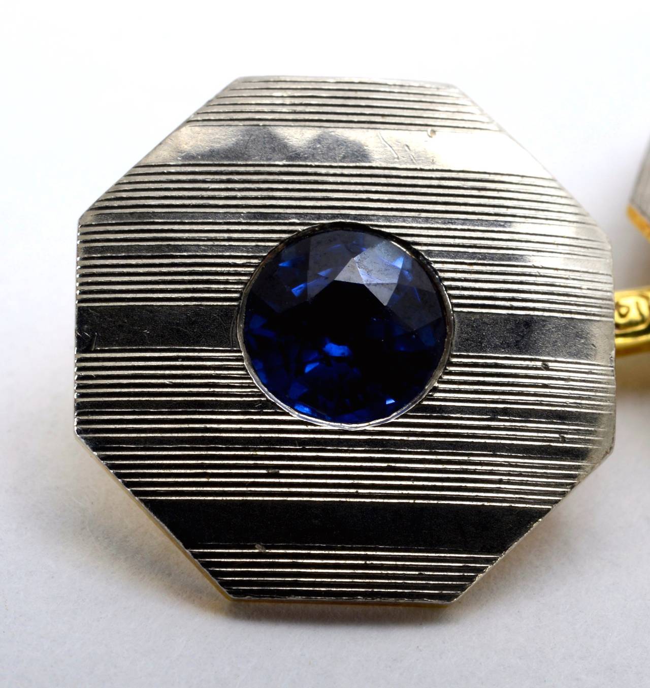 Blue Sapphire, Platinum and 18k Gold Art Deco Cufflinks c1925. Marked 'gold+plat.' The backs are 18k (tested) yellow gold with a gold connecting bar. The Platinum fronts with engraved decoration surround a round cut natural blue sapphire, each