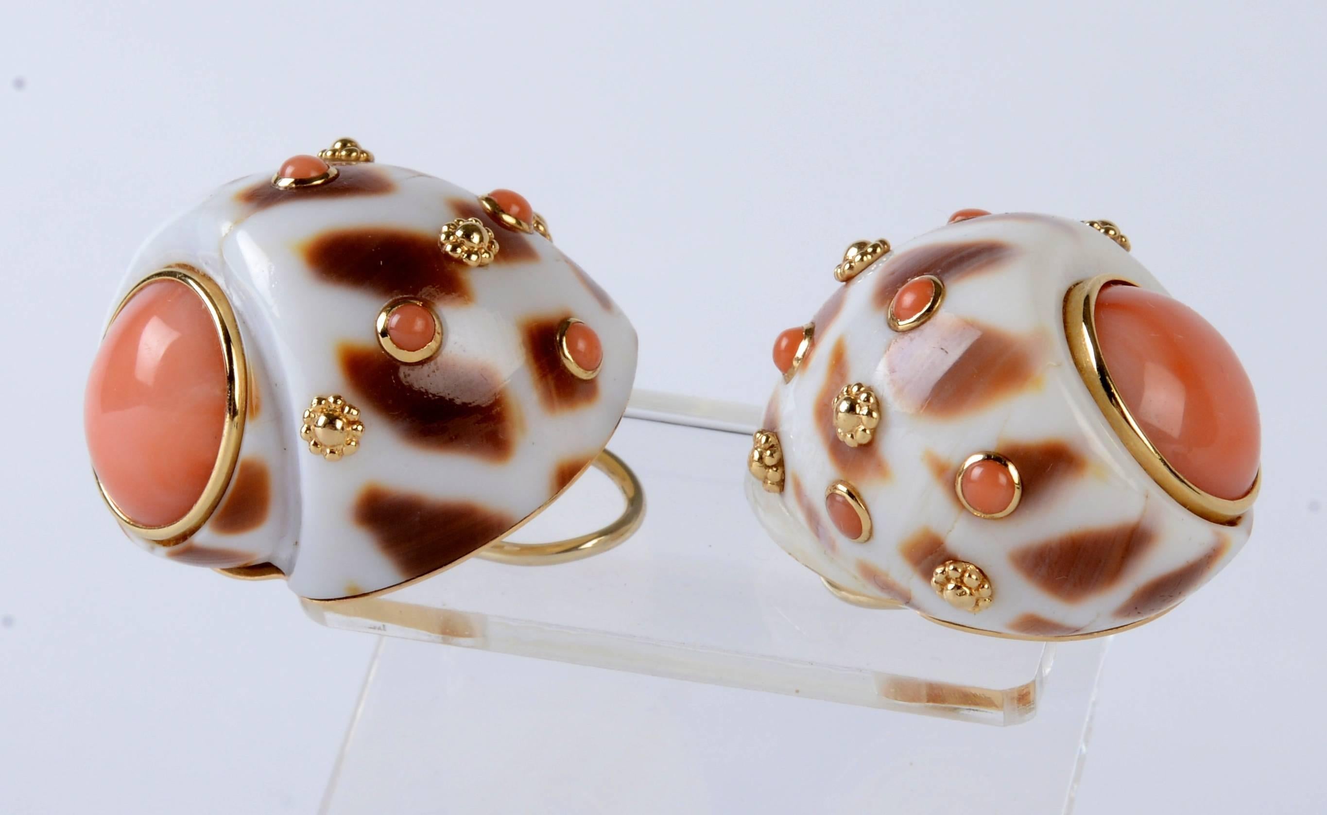 A Pair of Coral and Marked 14KT Gold Mounted Shell Earrings The Gaudi Nautica Shell has a 13mm, Bezel Set Cabochon Shaped Pink Coral with small floral shaped gold studs and bezel set cabochon coral stones. The gold backs have Omega style clips. It