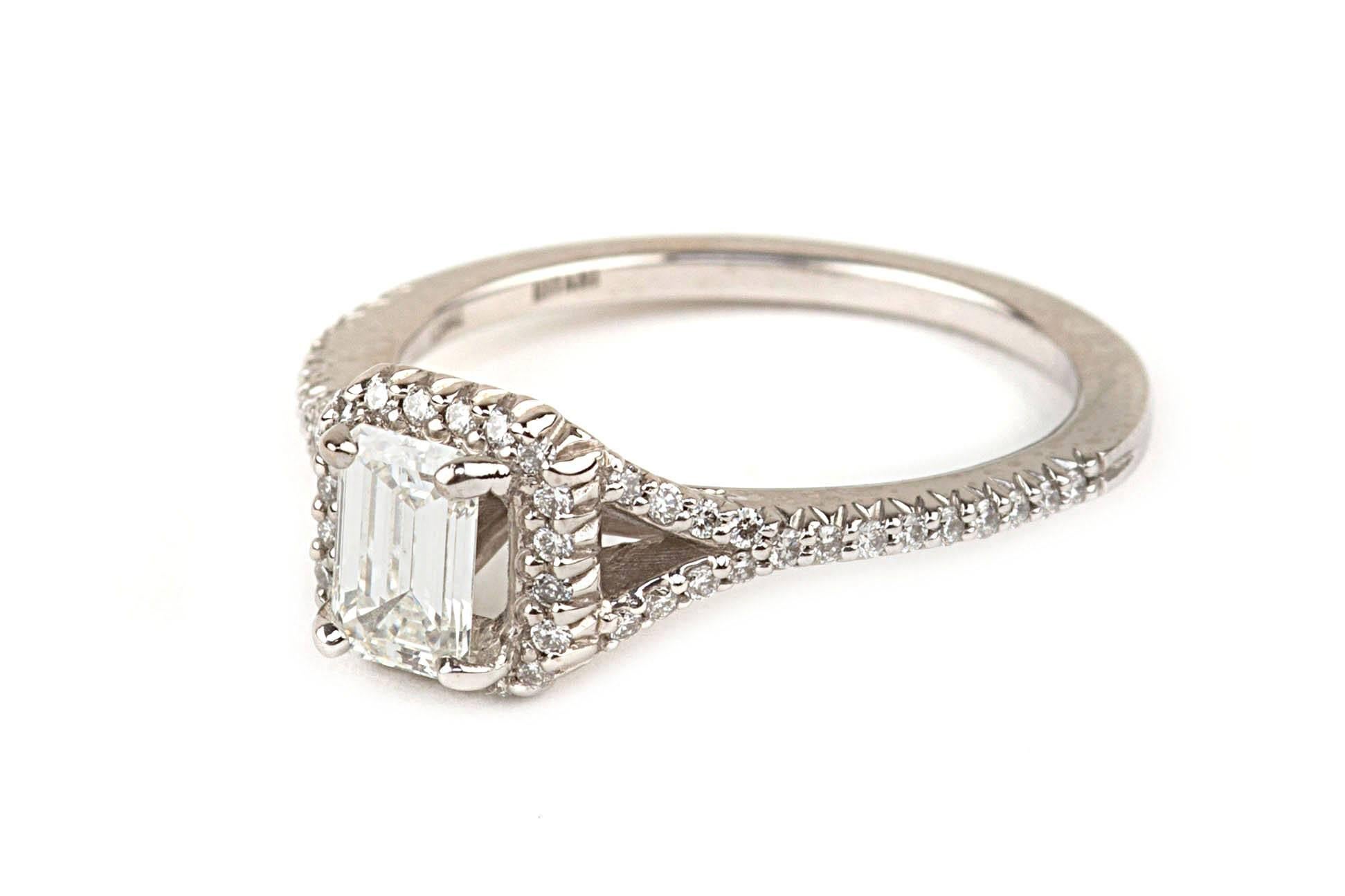 This sophisticated modern engagement ring features an 18 karat white gold diamond Ritani mounting. The  emerald cut diamond is .59 carats and has  a GIA certificate. The diamond is graded H/VS2, and GIA certificate number 1166061504. There are .25