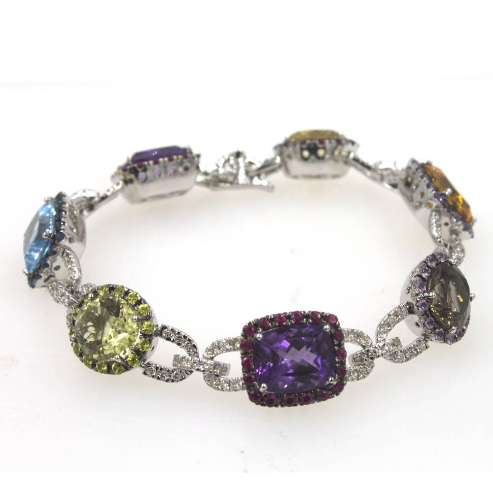 Beautifully crafted multi-color gemstone and diamond link bracelet. Diamonds, Sapphires, Rubies, Amethysts, Citrines, Topaz, and Quartz are all used in this 18 karat white gold bracelet. The round and cushion cut faceted gemstones are surrounded by