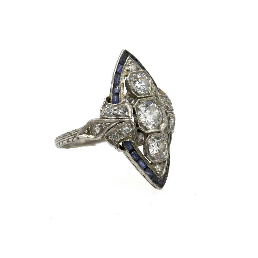 This fabulous original Art Deco Three Stone Ring features diamonds and accent sapphires set in an original platinum mounting. The Old European Cut diamonds together weigh approximately 1.15 cttw. The center diamond is approximately 1/2 carat, and
