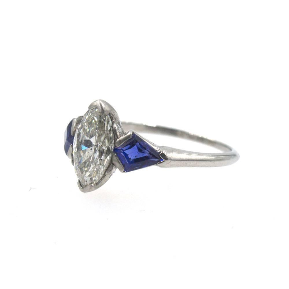 Original Diamond Engagement Ring Fashioned in Platinum. This diamond ring features an 1.11 marquise shaped center diamond with a GIA certificate. The diamond is graded J color and I1 clarity. Two beautiful blue sapphires are set on either side of