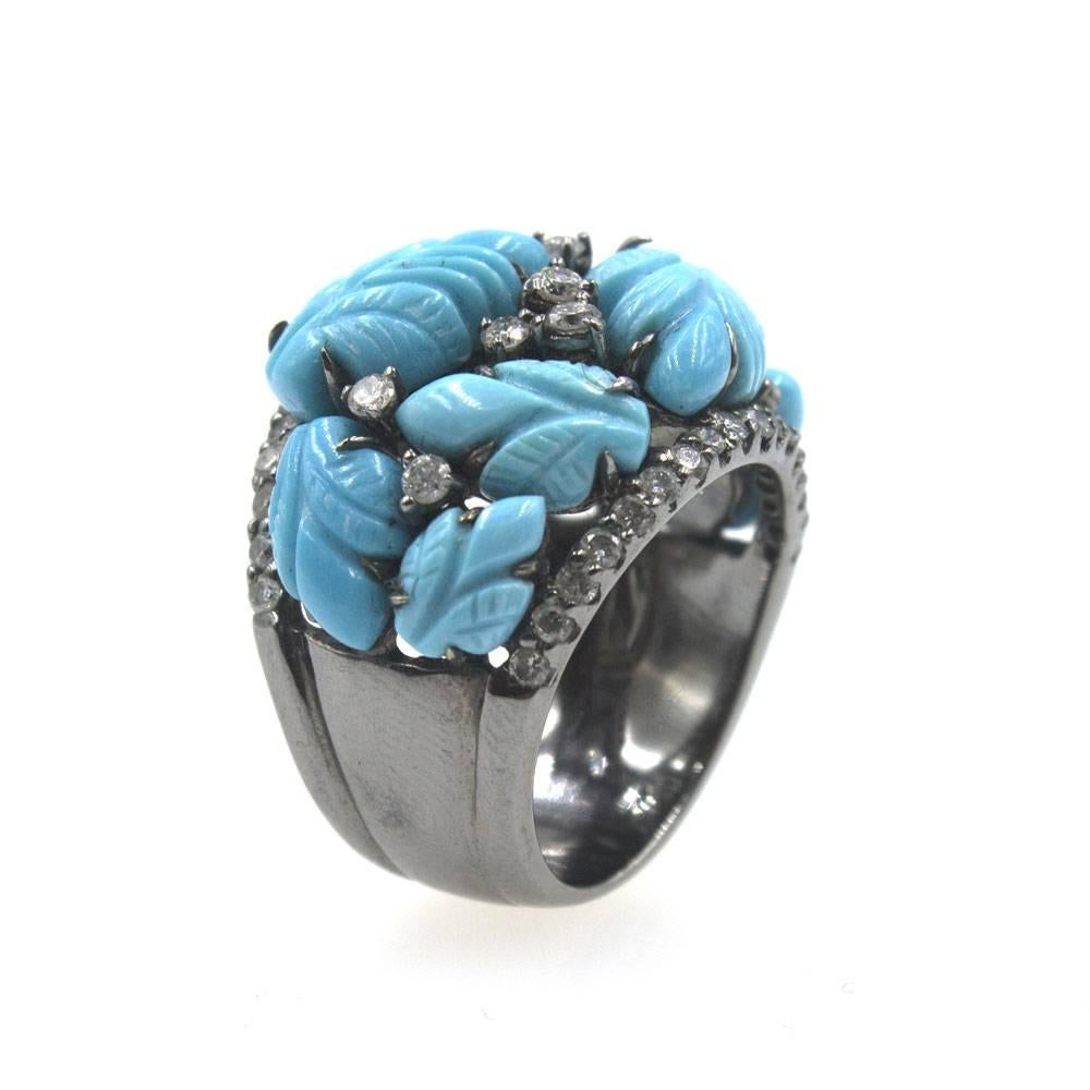 This fabulous turquoise and diamond fashion ring features carved turquoise gemstone and round brilliant cut diamonds. The 18 karat white gold ring has an oxidized finish. There are approximately .80 cttw of diamonds dispersed throughout the ring.