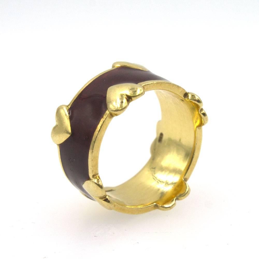 Fabulous enamel gold ring by Schlumberger for Tiffany & Company. The ring from the Late 20th Century is fashioned in 18 karat yellow gold with hearts along the border. The enamel is a burgundy red, and is great condition. The ring is size 7.5,