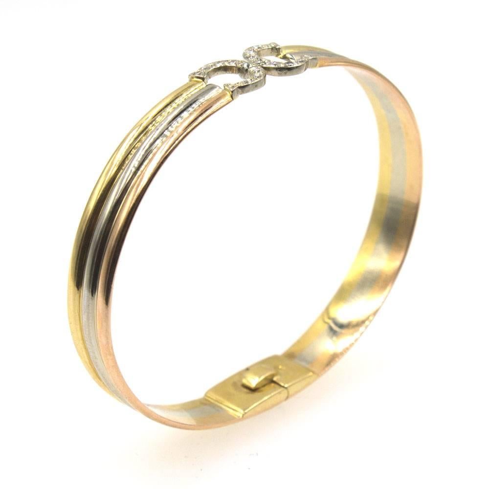  This Cartier tricolor gold bangle bracelet features Cartier's signature diamond CC clasp. The 8mm retro bracelet is a small size and will fit up to a 6.5 inch wrist.  Signed Cartier 750. The clasp contains 15 round brilliant cut diamonds that equal