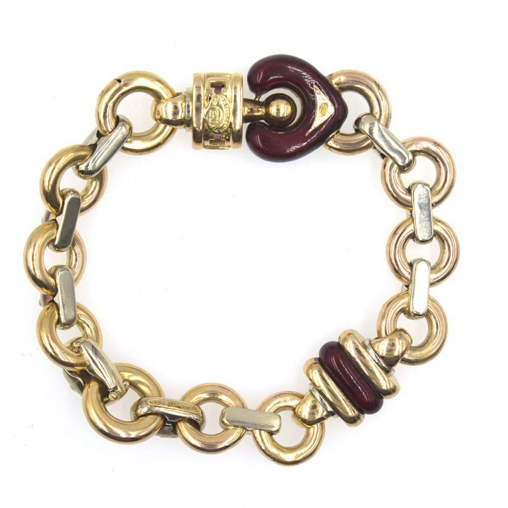 Stylish 18 karat yellow gold and sterling silver link bracelet by Italian designer Nouvelle Bague. This two-tone link bracelet features a red enamel heart link set with five ruby gemstones. The braclet measures 8 inches in length, .6 inches in