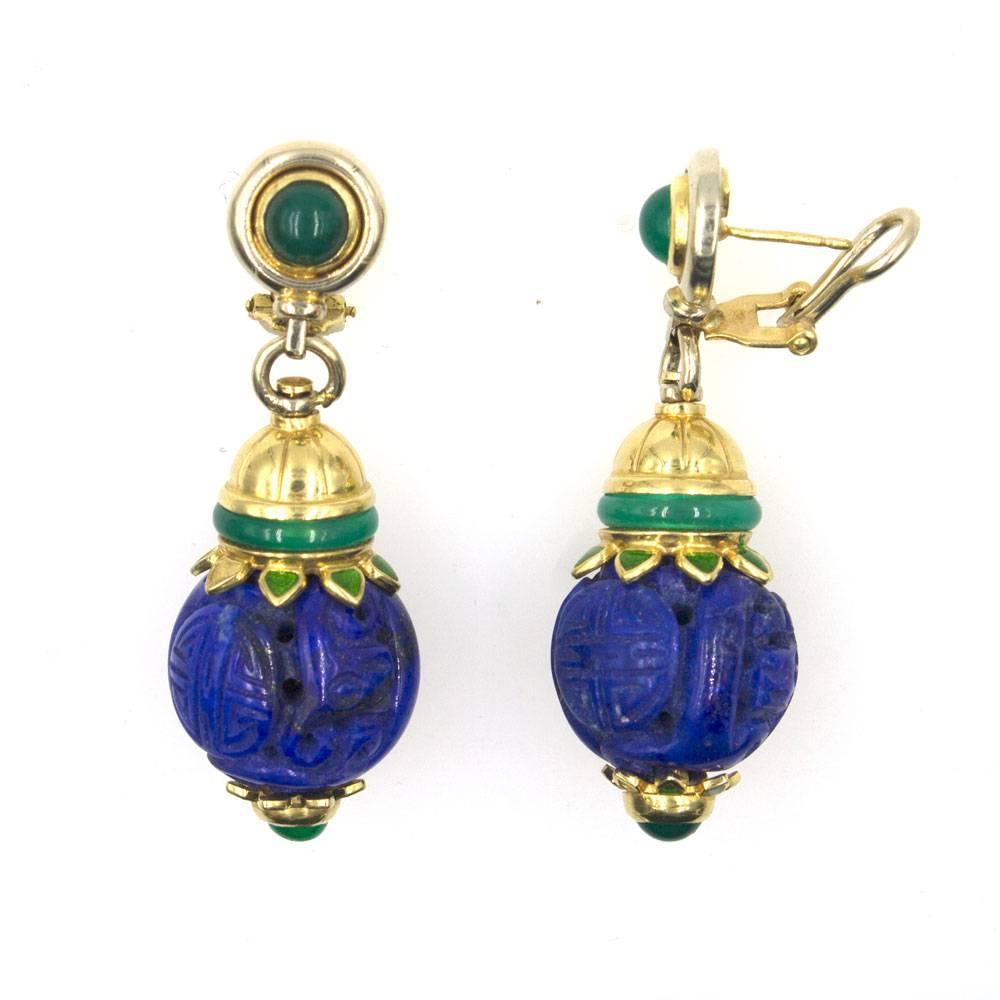 Beautifully crafted lapis and jade earrings from the Mid-20th Century. These colorful earrings feature carved round lapis gemstone, jade accents, and 18 karat yellow gold hardware. The drop earrings measure 2 inches in length, 18mm in width, and