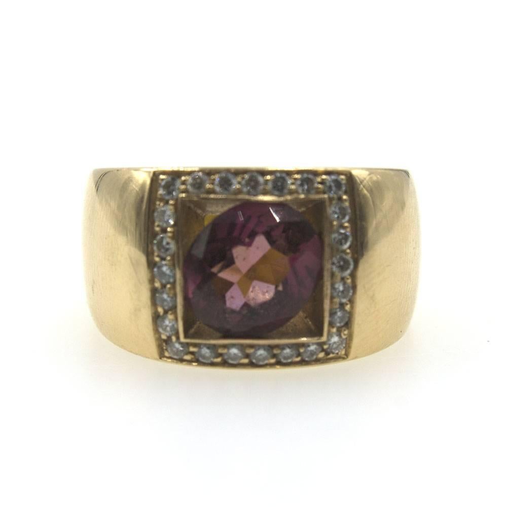 This  unique retro style fashion ring is crafted in 18 karat rose gold. The center rubelite gemstone is set on the diagonal in the center of the ring. Surrounding the rubelite are 24 round brilliant cut diamonds set in a square configuration. The