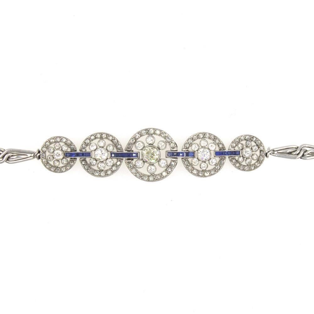 This original Art Deco bracelet features old European cut diamonds and sapphires beautifully crafted in platinum. The five filigree diamond circles are linked together with sapphire set links, and measure 15mm in width in the center of the bracelet,