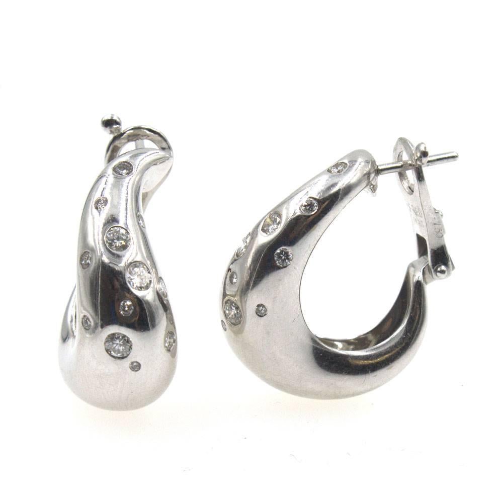 Stylish teardrop half hoop diamond earrings by Fred Paris. Beautifully crafted in 18 karat white gold, the earrings feature 24 bezel set diamonds in different sizes. All together the diamonds equal approximately .75 cttw. The earrings measure 22mm