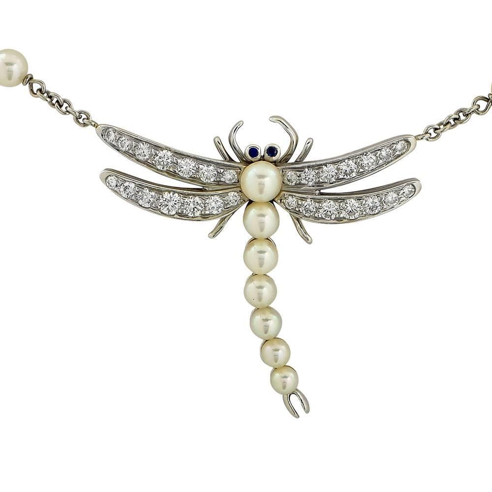 This fabulous dragonfly necklace by Tiffany & Co. is circa 1996. The gorgeous platinum dragonfly features diamond wings, cultured pearl body, and is linked to  a pearl and platinum 17 inch chain. The dragonfly also features sapphire eyes, and