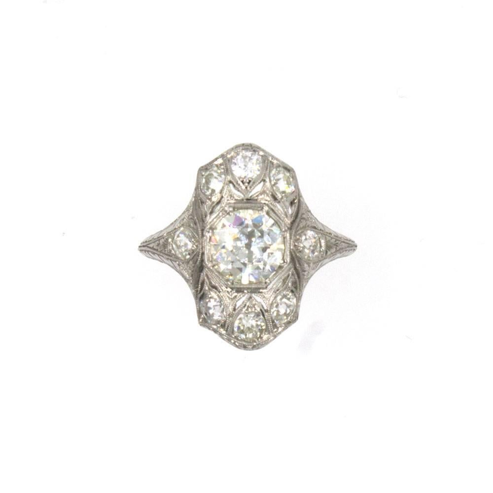 This original Art Deco diamond filigree ring is beautifully crafted in platinum. The center features an 1.38 carat Old European cut diamond graded J color and VS clarity. The vintage filigree mounting features 8 Old European cut diamonds that equal