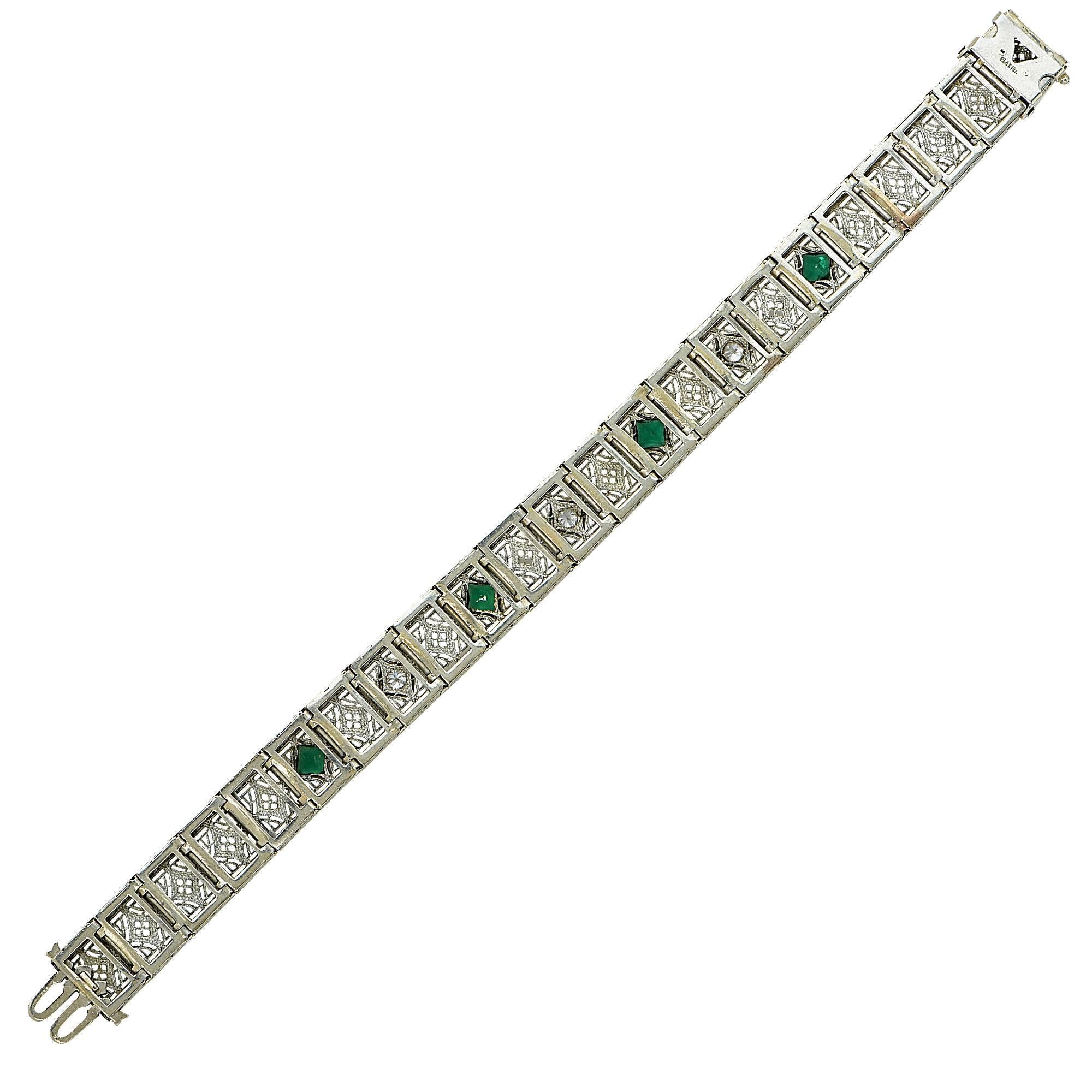 Beautiful platinum and white gold filigree bracelet from the Mid-20th Century. There are three brilliant diamonds that equal approximately .50 cttw, and four green non-precious stones. This vintage bracelet measures 7.25 inches in length and 12mm in