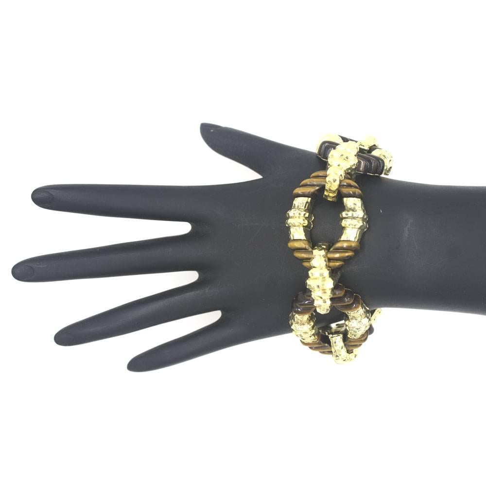 This beautiful 1960's link bracelet features carved tiger's eye gemstone and hammered 14 karat yellow gold bracelet. The stylish bracelet measures 8.25 inches in length and 1.0 inch in width.  