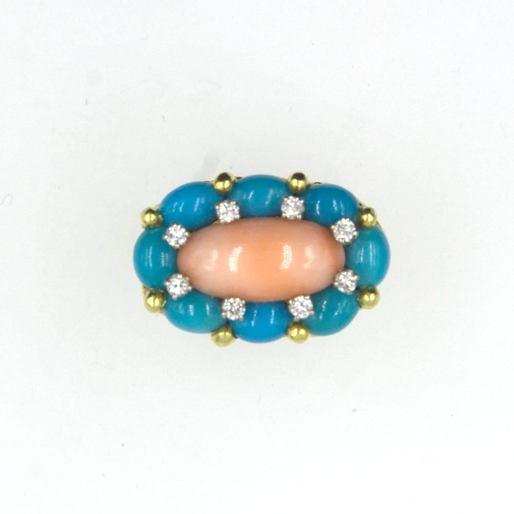 This fabulous 1960's fashion ring features coral, turquoise, and round brilliant cut diamonds. Coral gemstone is surrounded by 8 turquoise gemstones and 8 diamonds. The shank is fashioned in textured 18 karat yellow gold. The top measures 18 x 26mm