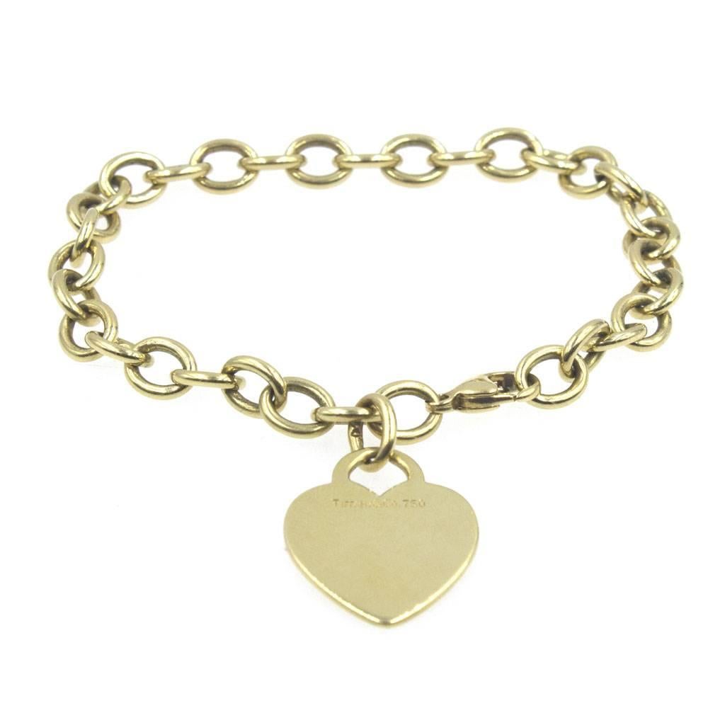 Tiffany & Company 18 karat yellow gold heart charm link bracelet. The heart is signed Tiffany & Co. 750. The Tiffany link bracelet measures 7.5 inches in length, and comes in a Tiffany jewelry pouch. 