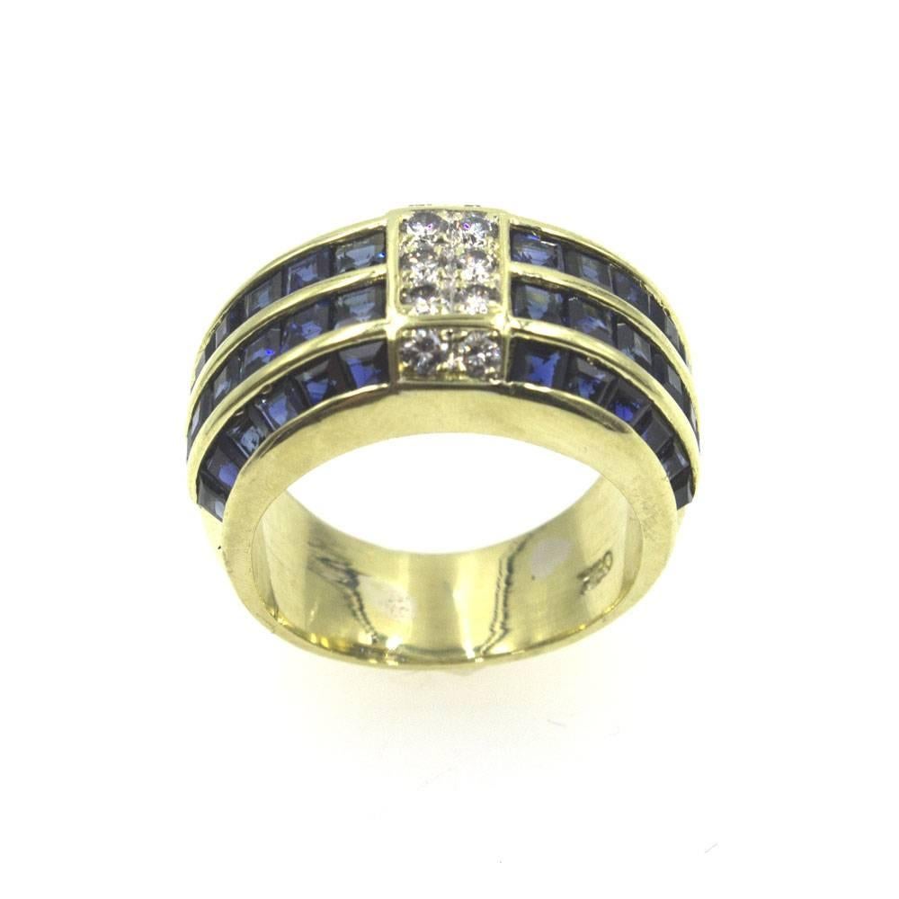 This beautiful sapphire and diamond band is fashioned in 18 karat yellow gold. The center of the band features 10 round brilliant cut diamonds surrounded by 4 rows of 48 blue sapphires on either side. The ring is size 6 (can be sized), and measures