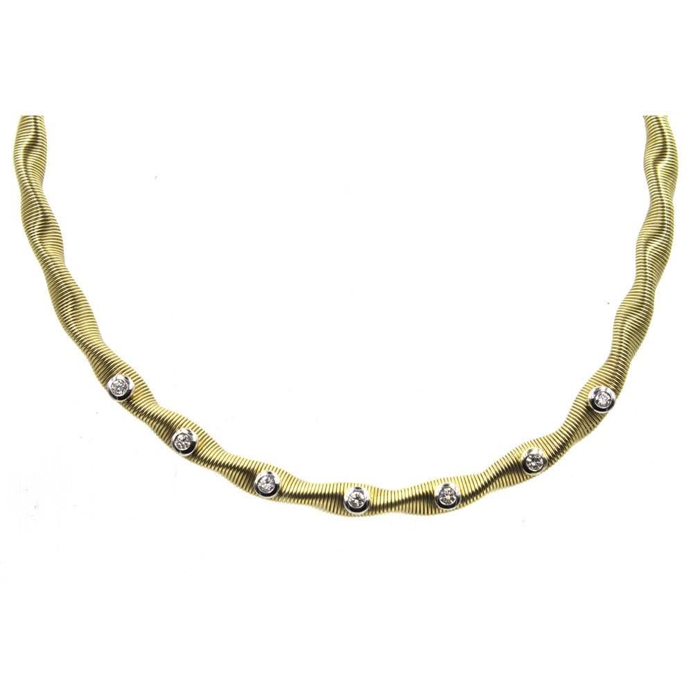 This modern diamond flexible yellow gold necklace features 7 bezel set round brilliant cut diamonds set in white gold. The 7 diamonds weigh approximately 1.00 carat total weight and are graded I color and SI1 clarity. Measuring 6.5mm in width, the