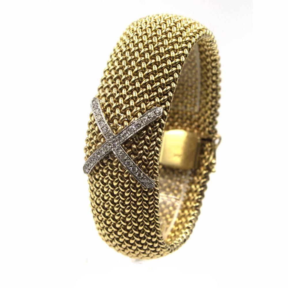This stylish wide diamond X soft bangle bracelet is fashioned in 14 karat yellow gold. The diamond  X features 29 round brilliant cut diamonds that equal approximately 1.00 carat total weight. Measuring 1.0 inch in width and 7.5 inches in length,
