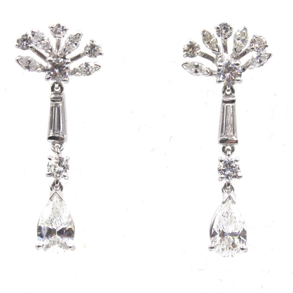These gorgeous diamond platinum drop earrings are circa 1950s. The earrings feature fan shaped tops with diamonds and diamond drops. There are two pear shaped diamonds that equal approximately 1.70 carat total weight and another 1.80 carat of