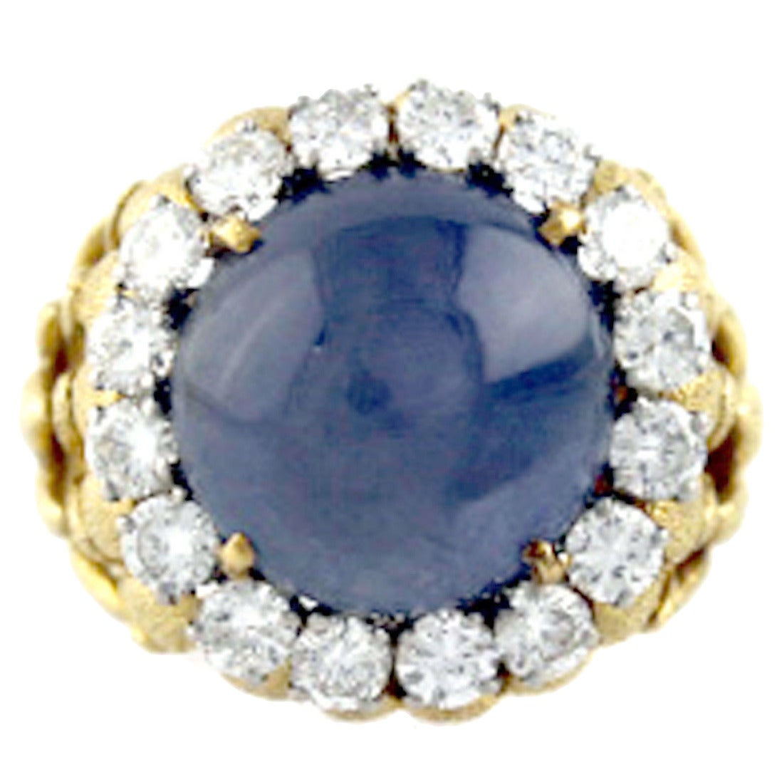 18 karat yellow gold ring by renowned designer Webb.  The ring features one cabochon cut star sapphire gemstone weighing approximately 18 carats.  Set in platinum surrounding the star sapphire are sixteen round brilliant cut diamonds weighing