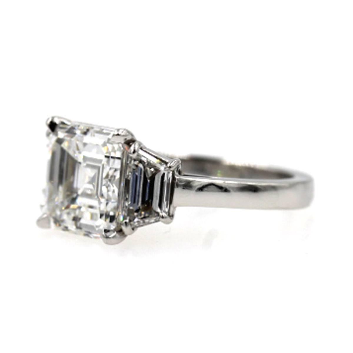 Gorgeous 3 diamond engagement ring by Cartier. The center diamond is a 3.17 carat Asscher cut graded F/SI1. The Diamond has a GIA certificate #14821675. Two side trapezoid shaped diamonds equal 1.00 carat total weight. The ring comes with original