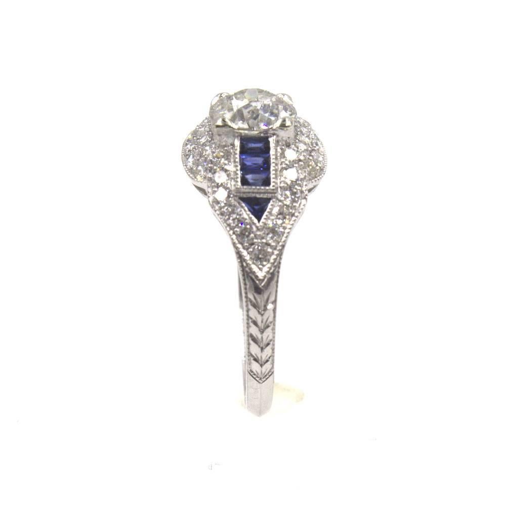 This stunning  ring features a lovely mix of old world diamonds and sapphires. The center .87 carat Old European Cut diamond is set in a diamond and sapphire platinum mounting. The center diamond is graded I color and I2 clarity. The mounting is set