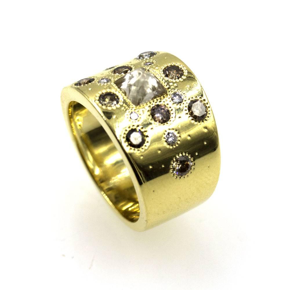 This stylish diamond and 18 karat yellow gold band is part of De Beer's Talisman Collection. Crafted with 1.32 carats of white, rough, and fancy colored diamonds, the ring measures .50 inches in width and is currently size 5 (can be sized). Signed