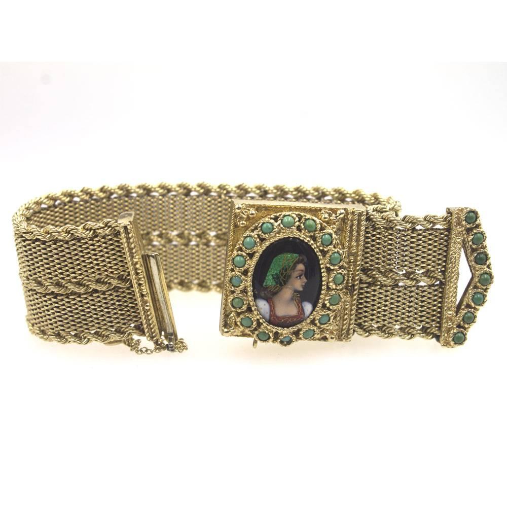 This portrait cover watch circa 1950's is fashioned in 14 karat yellow gold. The mesh wide bracelet measures 1.0 inch in width and 7 inches in length. Turquoise gemstones surround the portrait cover and accent the buckle. The geneva movement is