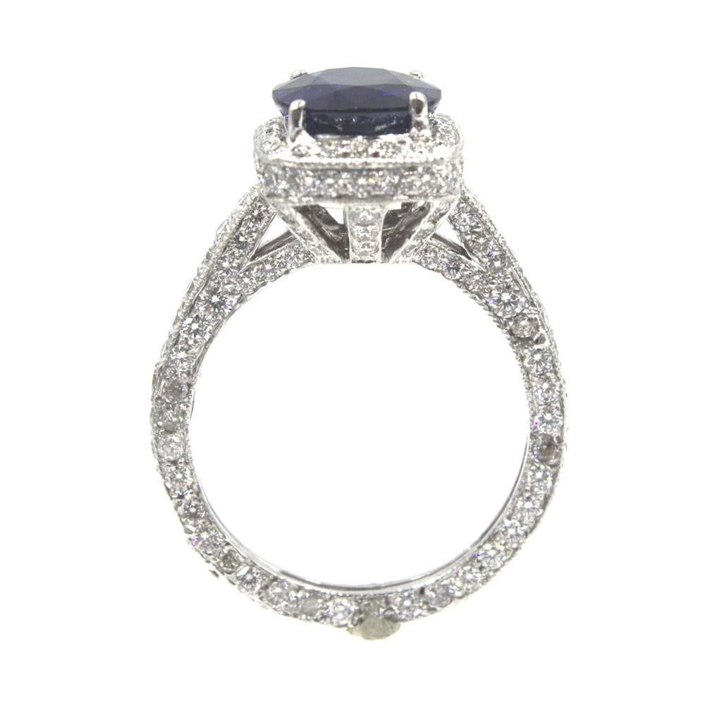 This gorgeous 3.31 cushion shape sapphire has a deep brilliant blue hue. The natural sapphire is mounted in a platinum mounting covered in diamonds. There are approximately 2.00 carat total weight of diamonds in this modern band. The ring is