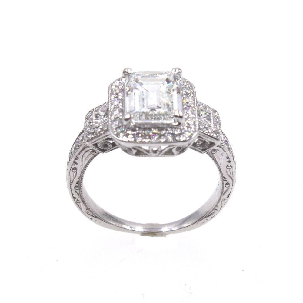 Elegant emerald cut diamond engagement ring. This timeless ring features a GIA certified 1.73 carat emerald cut diamond graded G color and VS1 clarity. Set in an 18 karat white gold halo mounting, there are approximately  another .50 carat total