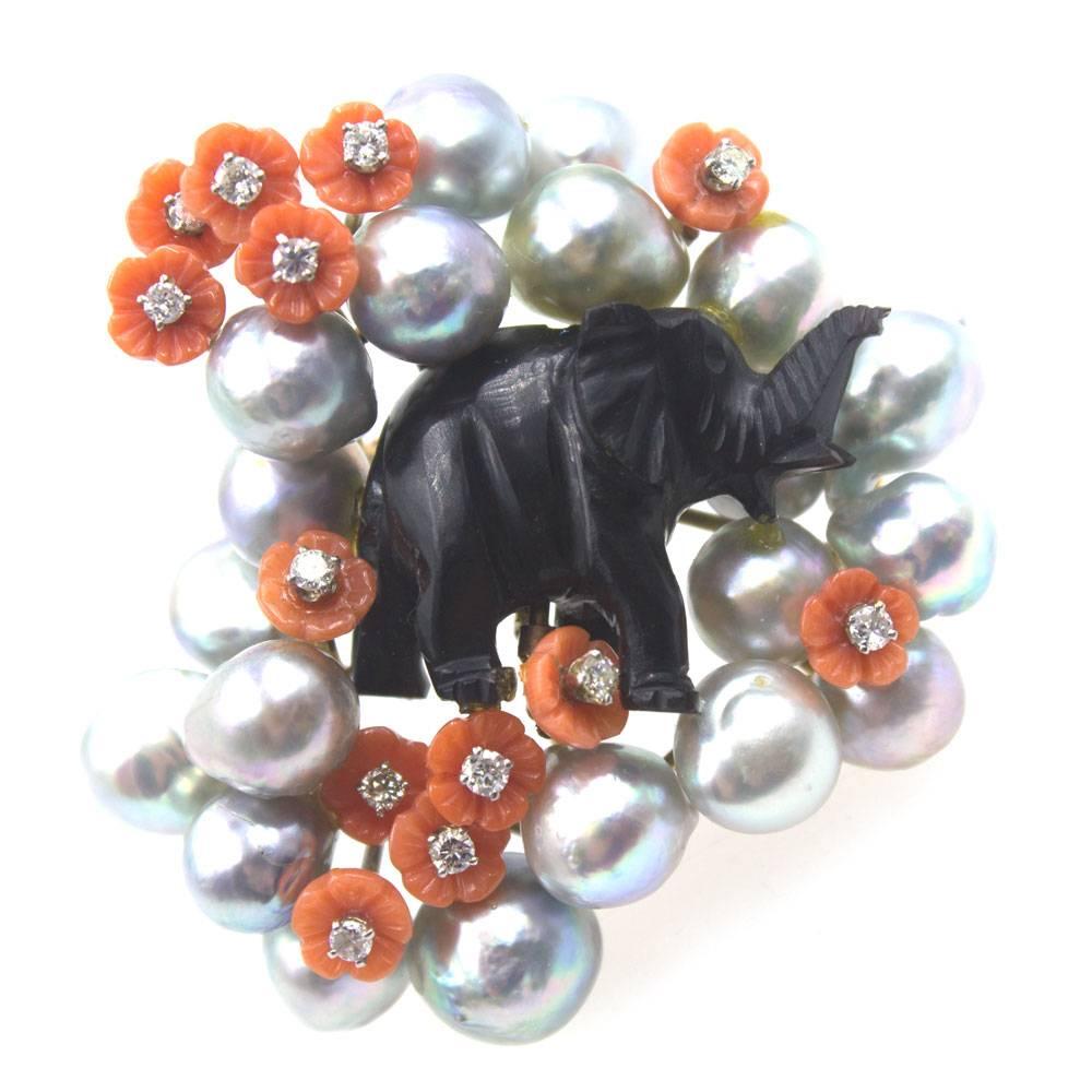 This fabulous piece of art features an elephant carved from obsidian gemstone. The black carved elephant is surrounded by grey pearls, coral carved flowers, and diamond accents. The 13 round briliant cut diamonds equal approximately .75 carat total