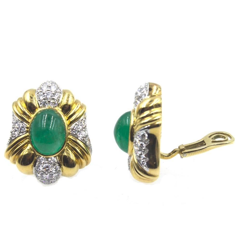 Impressive emerald and diamond clip earrings are circa 1970's. The earrings feature two large cabochon emeralds weighing approximately 20.0 carat total weight. Textured 18 karat yellow gold and 76 round brilliant cut diamonds (3.50 carat total