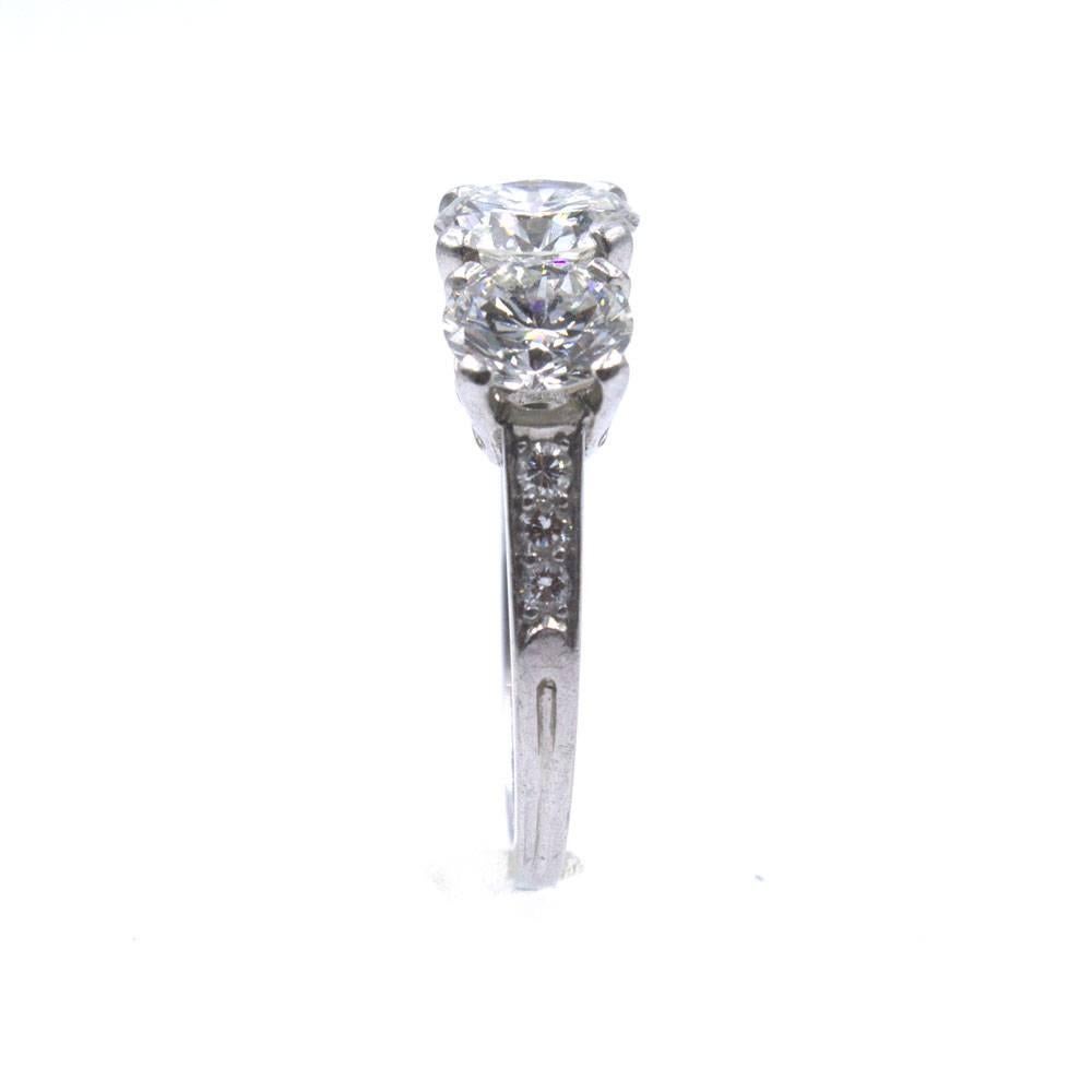 This timeless Tiffany & Company Three Diamond Ring is beautifully crafted in platinum. The ring features three round brilliant cut diamonds graded G-H color and VS clarity. The center diamond is  1.12 carats, and the side diamonds measure .82 and