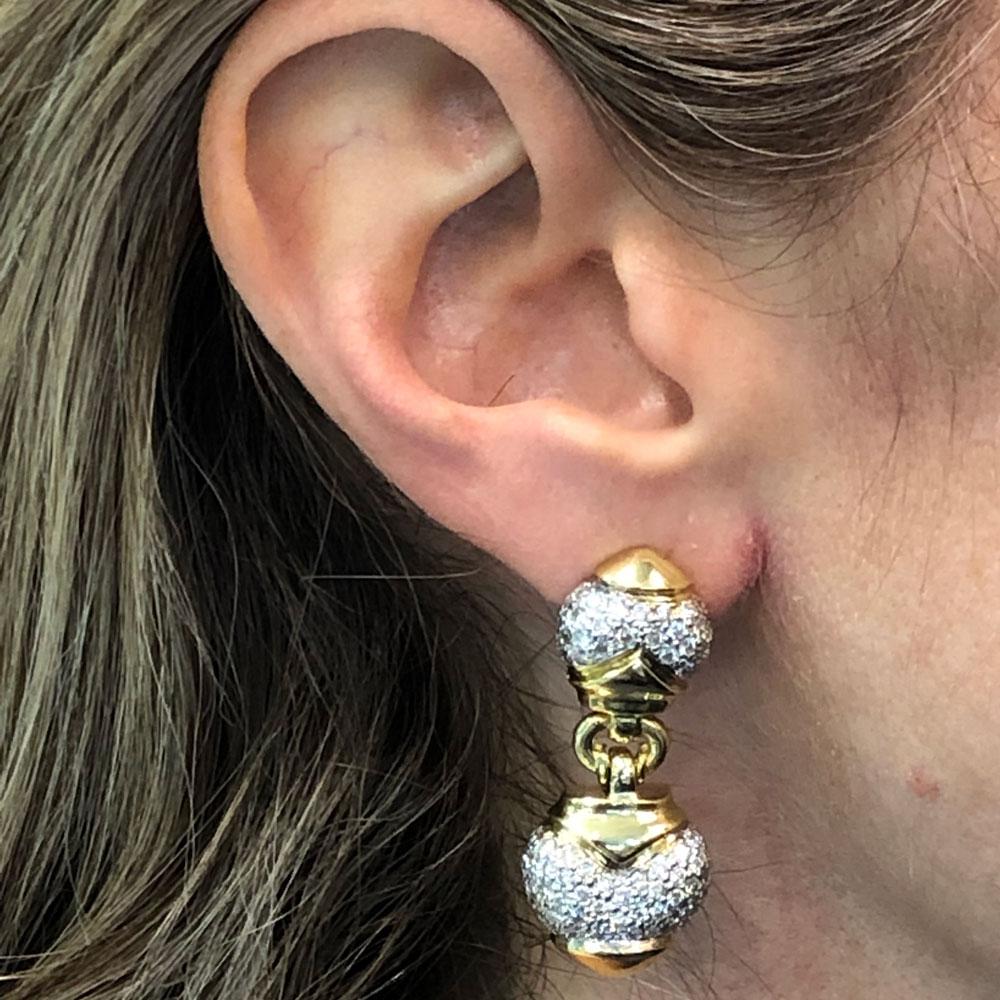 Beautiful pave diamond drop earrings crafted in 18 karat two tone gold. The drop earrings feature 2.00 carat total weight of round brilliant cut diamonds graded G-H color and VS2-SI clarity. Measuring 1.5 inches in length and .60 inches in width,